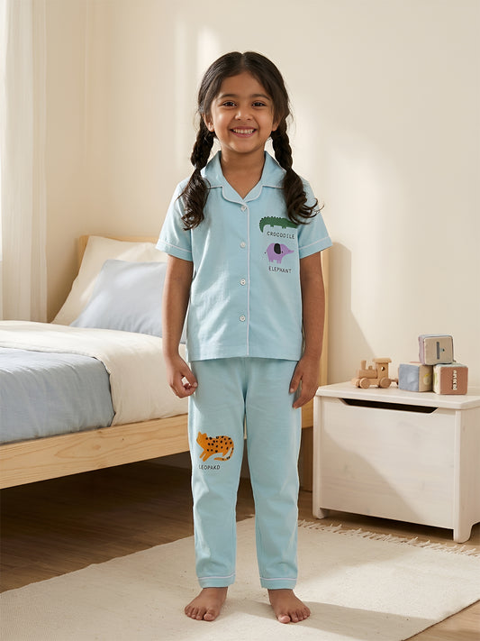 Young girl wearing light blue pajamas with animal prints in a bedroom setting.