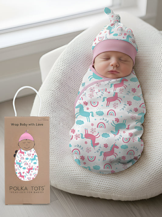 Newborn baby swaddled in a colorful blanket with a hat, sitting on a white cushion next to a Polka Toys product box.