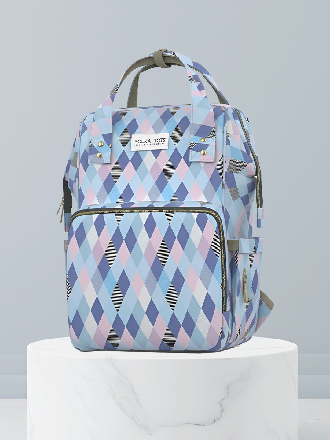 Backpack with blue and pink diamond pattern on a white pedestal against a light gray background