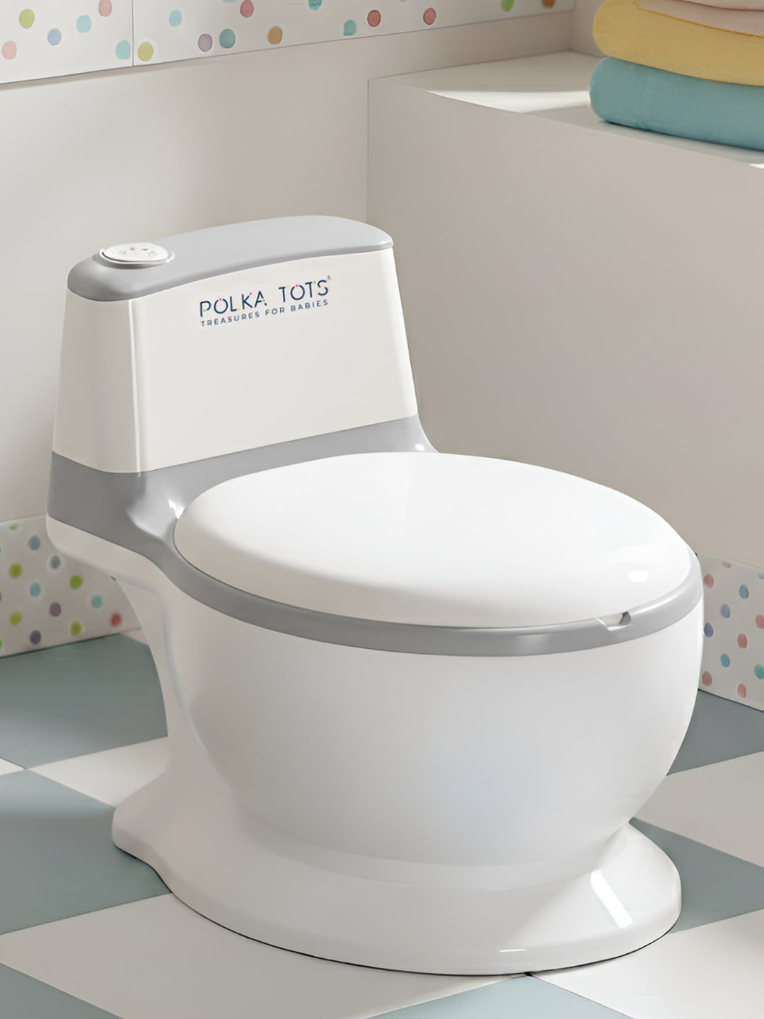 White children's toilet seat with 'Polka Tots' branding on a bathroom floor.