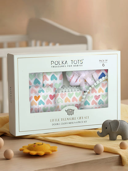 Polka Tois baby gift set packaging with heart patterns on a wooden surface.
