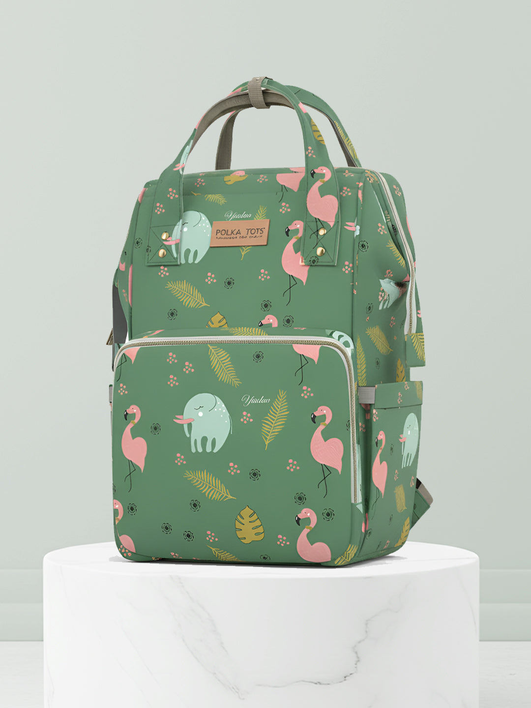 Green backpack with flamingo and elephant pattern on a light gray background