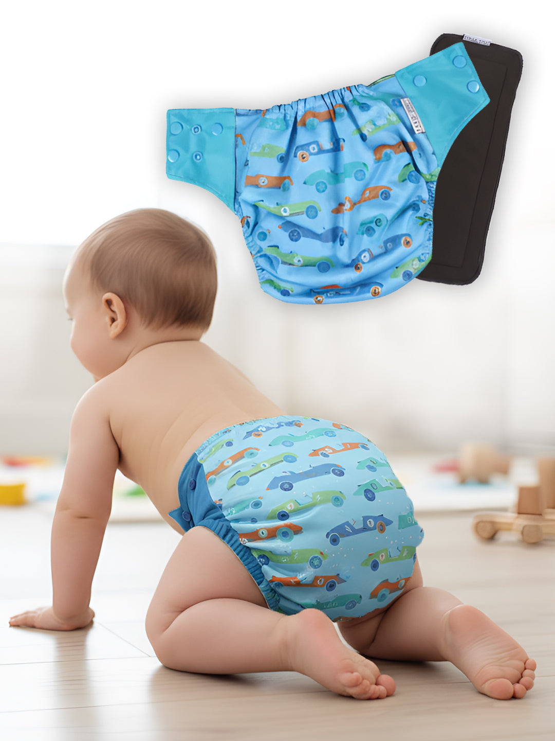Baby wearing a blue diaper with car pattern, with another similar diaper hanging in the background.