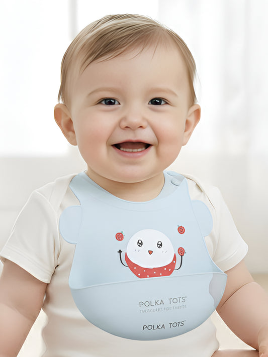 Baby wearing a light blue bib with a cartoon character and 'Polka Tots' branding.