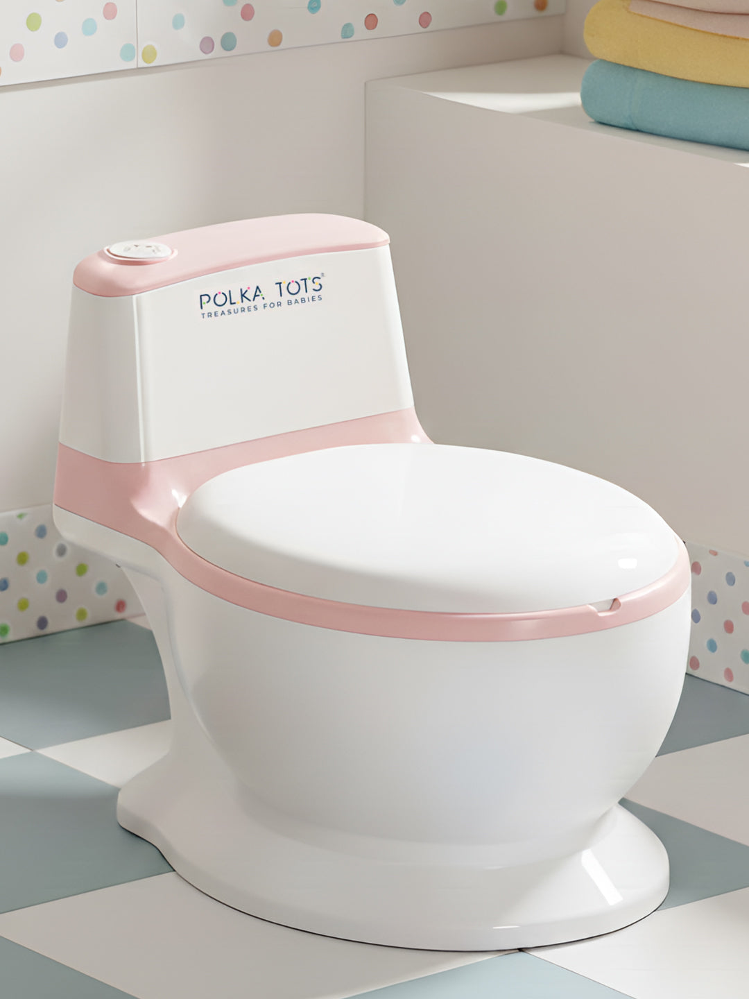 White and pink children's toilet with 'Polka Tots' branding on a checkered floor.