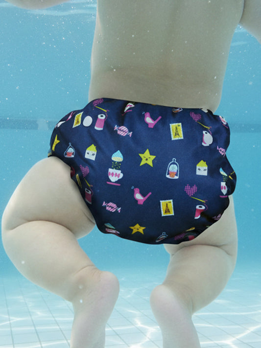 Navy swim diaper with colorful patterns on a doll against a pool background