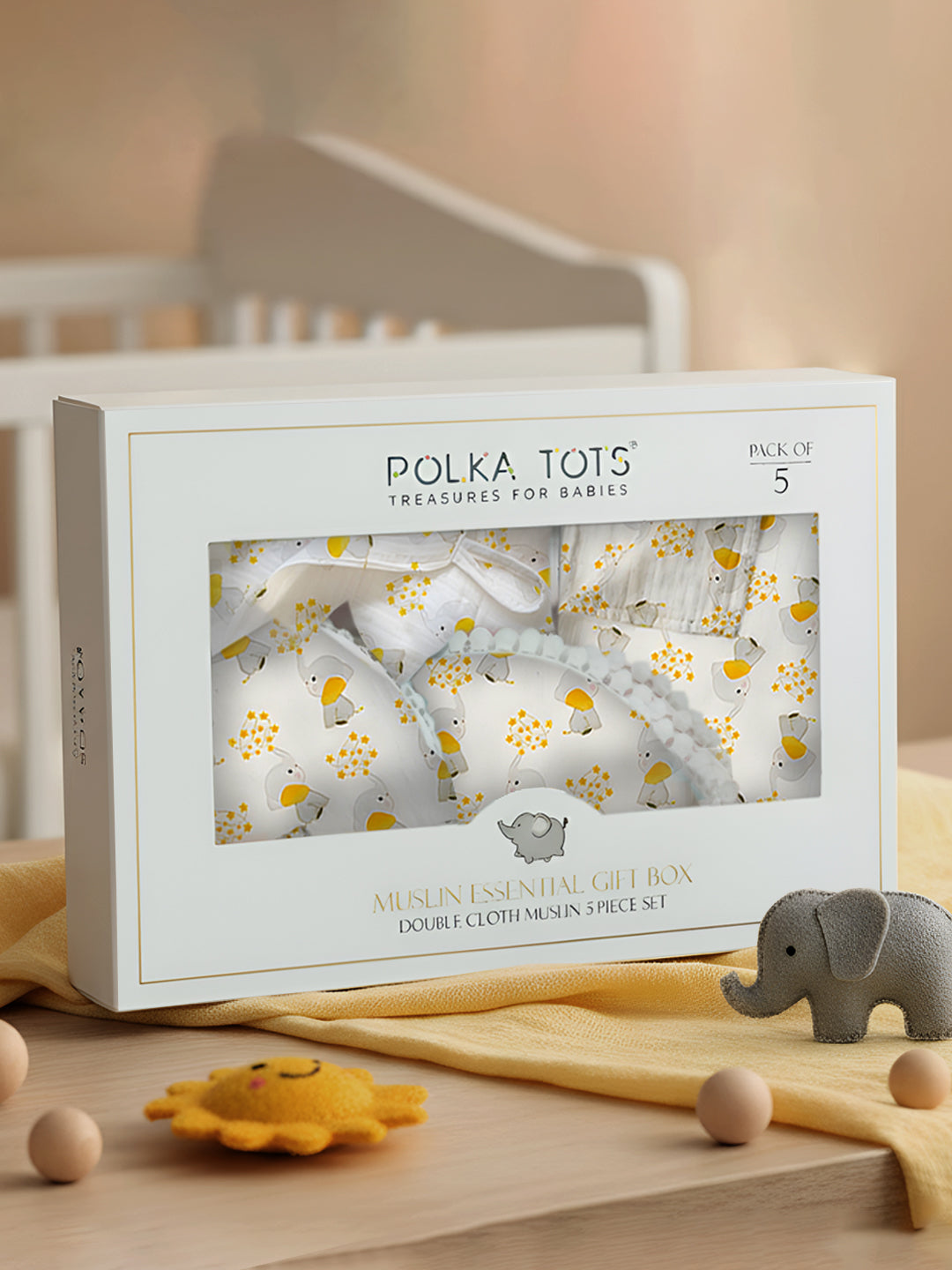 Polka Tots baby product packaging with elephant toys on a wooden surface