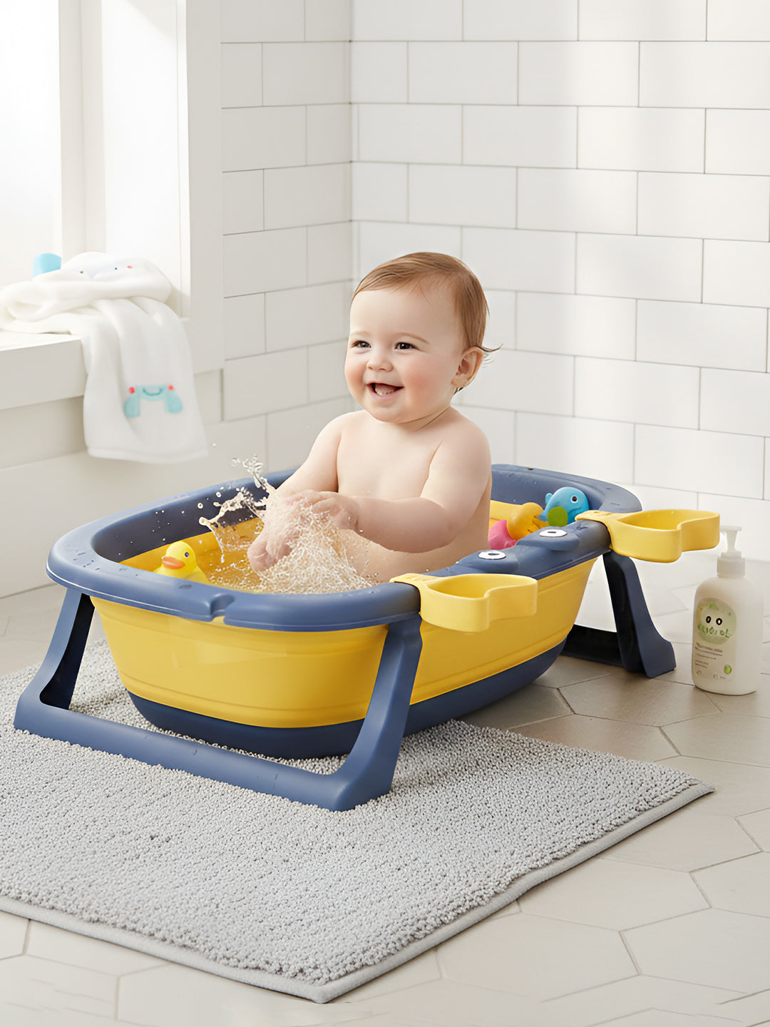 Baby sitting in a yellow and blue baby bath seat with toys in a bathroom.