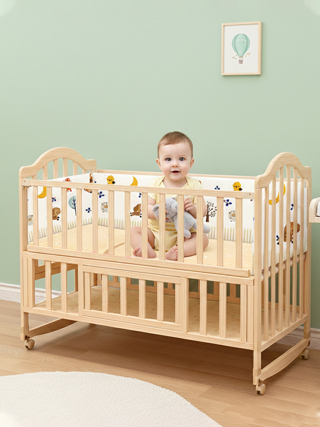 Baby standing inside a wooden crib with a light green wall and framed picture in the background.