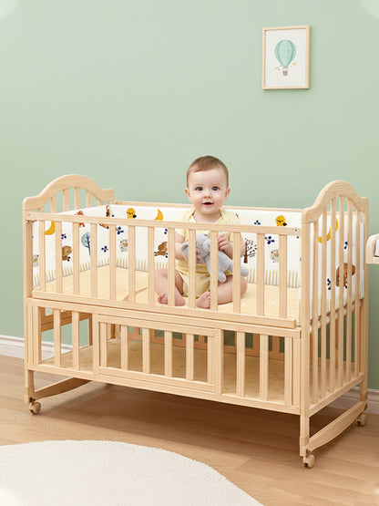 Baby standing inside a wooden crib with a light green wall and framed picture in the background.