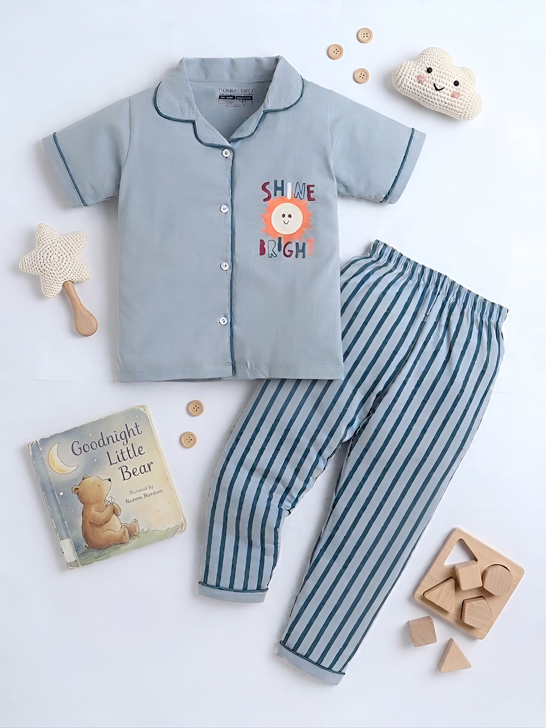 Children's pajama set with striped pants and a shirt, surrounded by toys and a book on a white background.