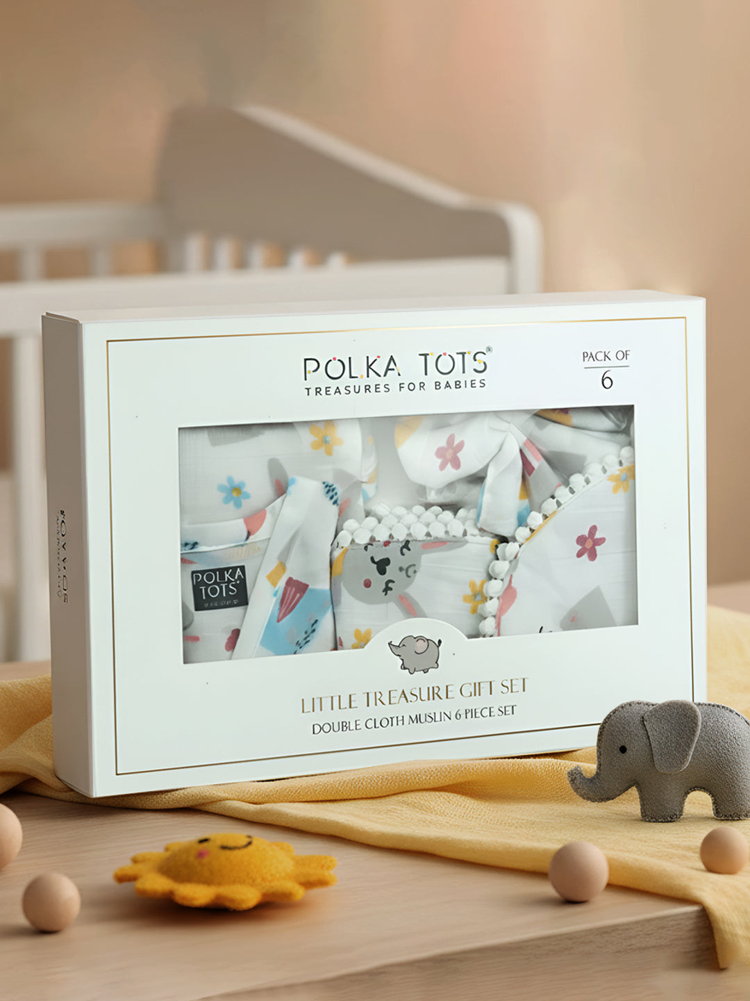 Polka Tots baby gift set packaging with baby items and toys on a wooden surface.