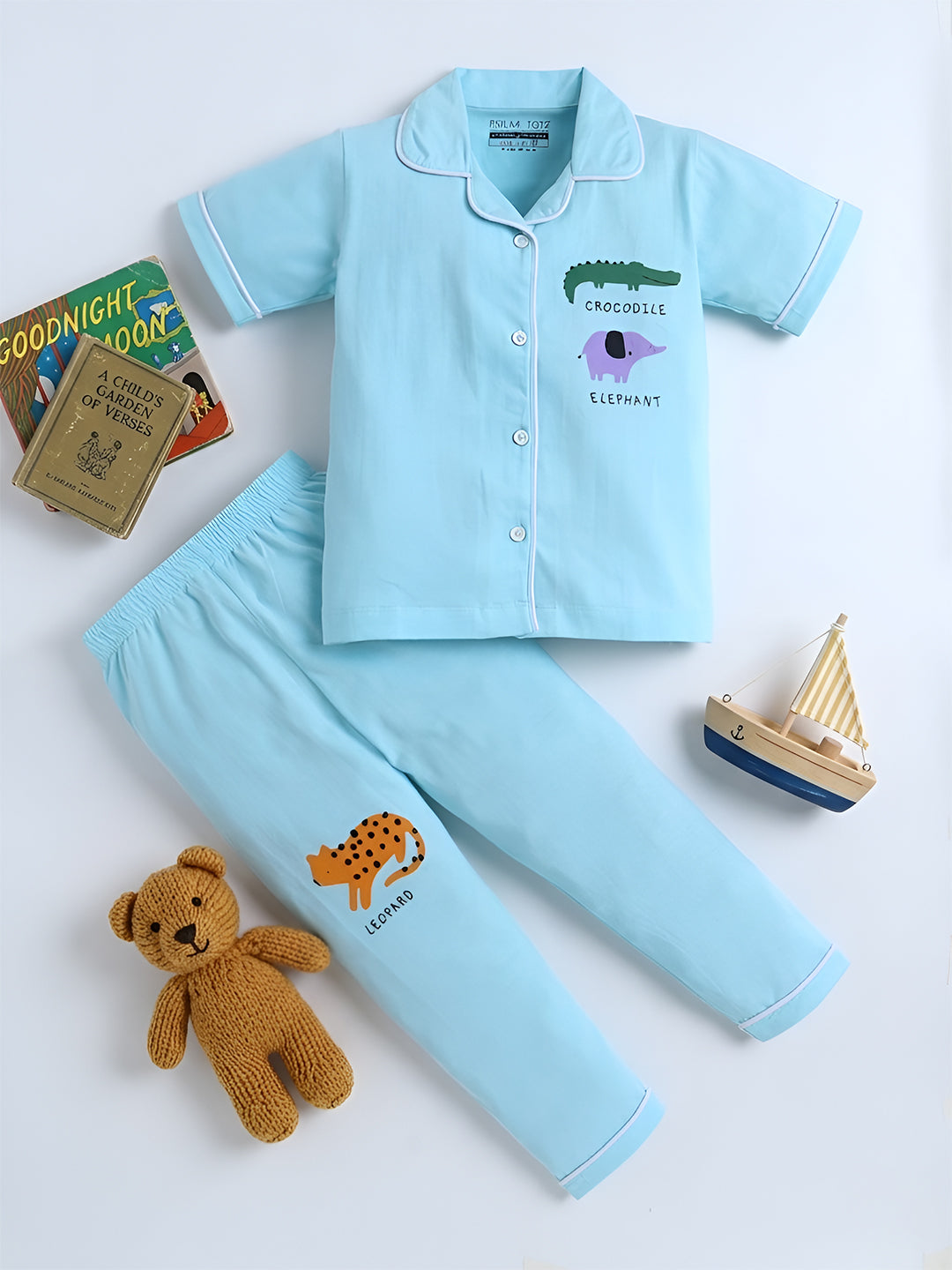 Children's blue pajama set with animal designs, teddy bear, and books on a white background
