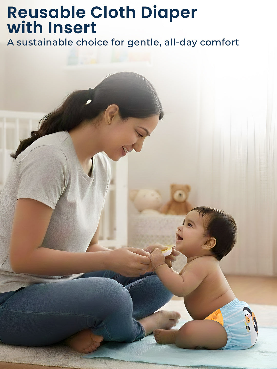 Woman sitting on the floor with a baby wearing a reusable cloth diaper in a bright room.