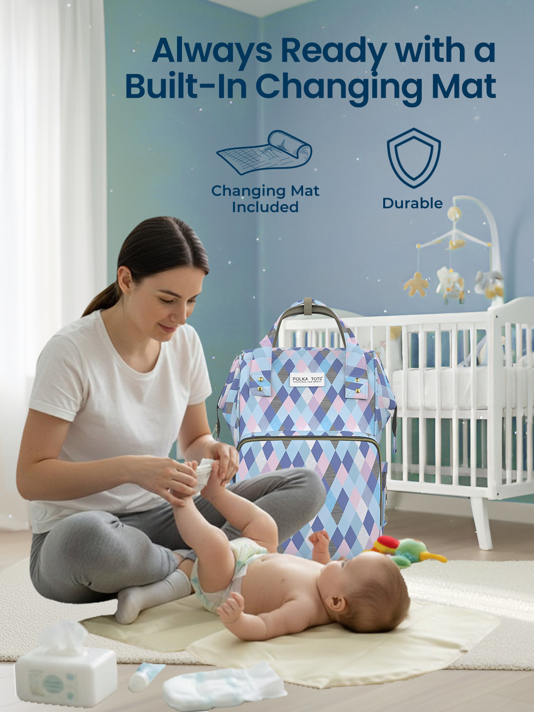 Woman changing a baby on a built-in changing mat with a blue patterned bag in the background.