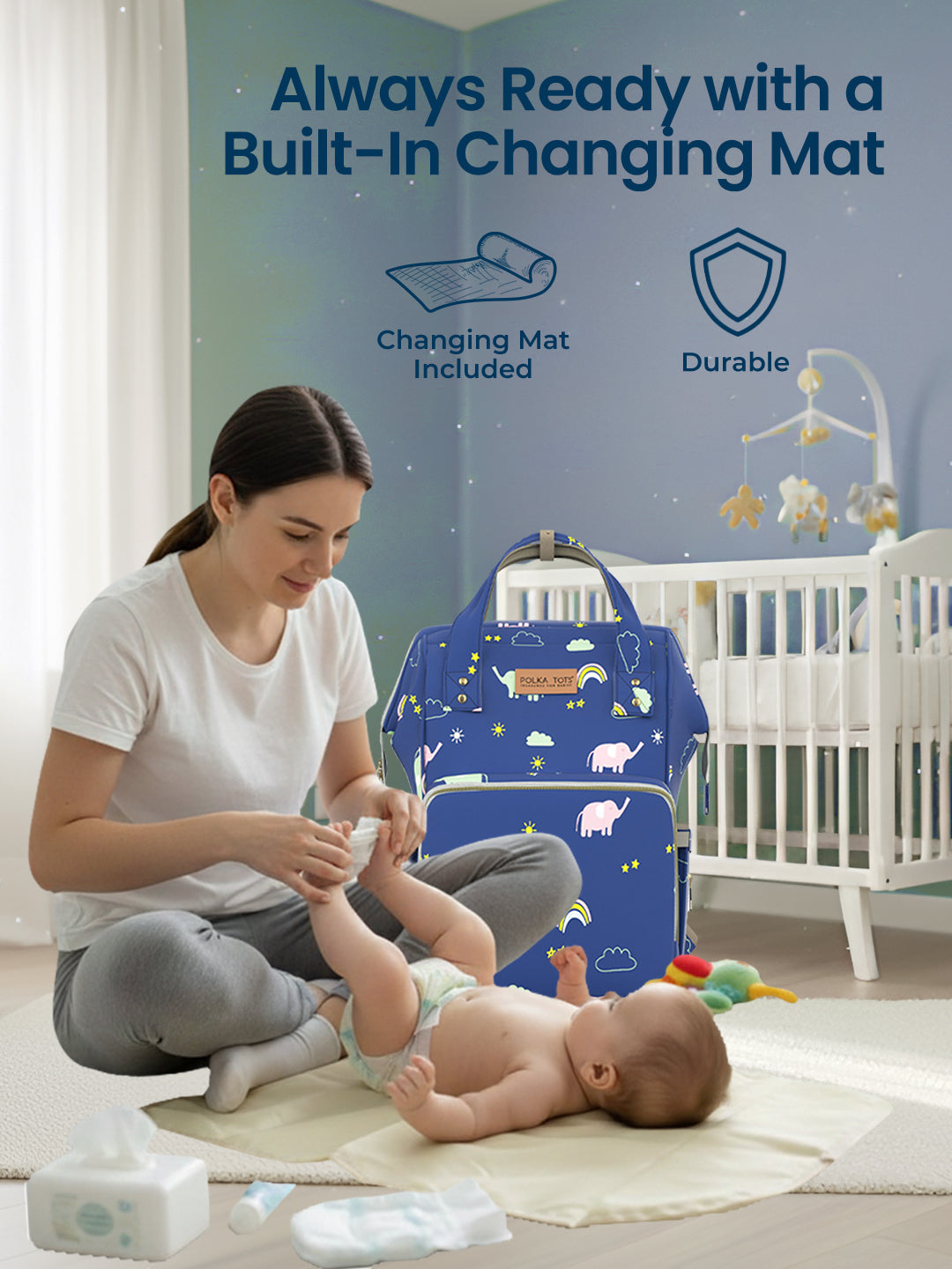 Woman changing a baby on a changing mat with a blue bag labeled 'Always Ready with a Built-In Changing Mat' in the background.
