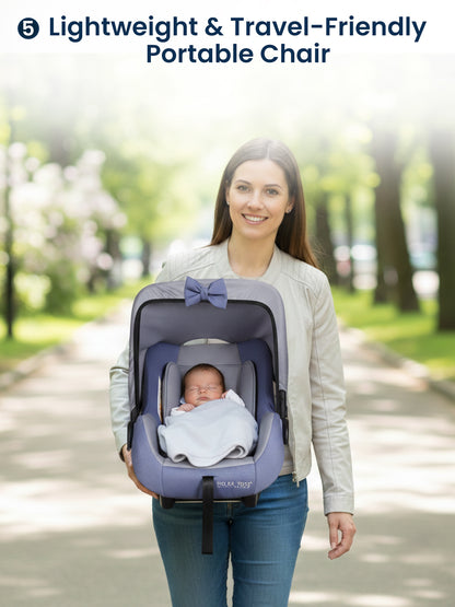 Woman carrying a baby in a portable chair with a park background