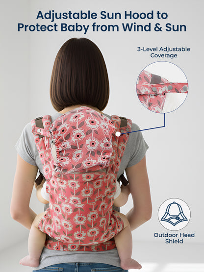 Woman using a baby carrier with an adjustable sun hood to protect baby from wind and sun, on a plain background.