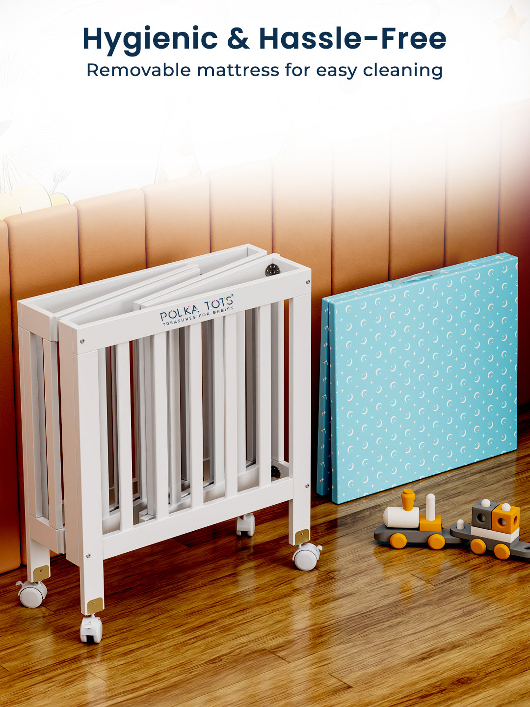 White crib with a blue mattress next to it on a wooden floor, with text 'Hygienic & Hassle-Free' and 'Removable mattress for easy cleaning'.