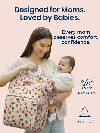 Woman holding a baby and a patterned backpack with text 'Designed for Moms. Loved by Babies.' on a light pink background.