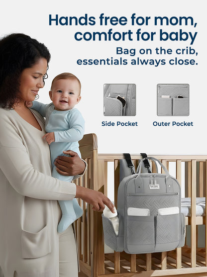 Woman holding a baby next to a gray diaper bag with text about its features.
