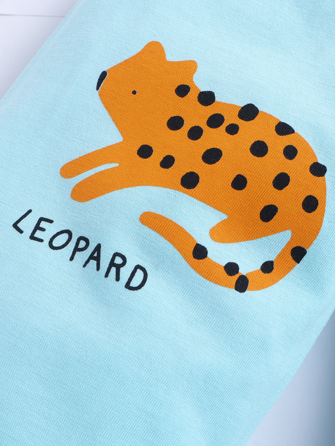 Orange leopard illustration with black spots on a light blue background