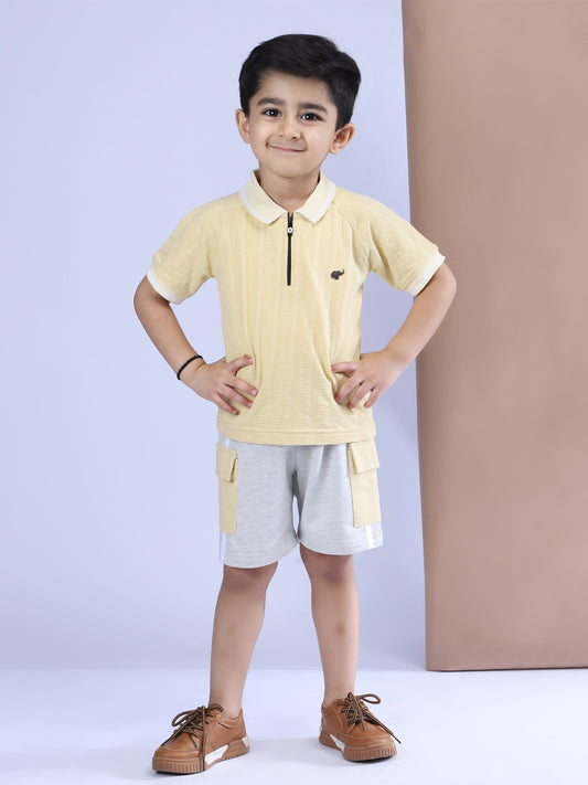Child wearing a yellow polo shirt and gray shorts against a light purple background