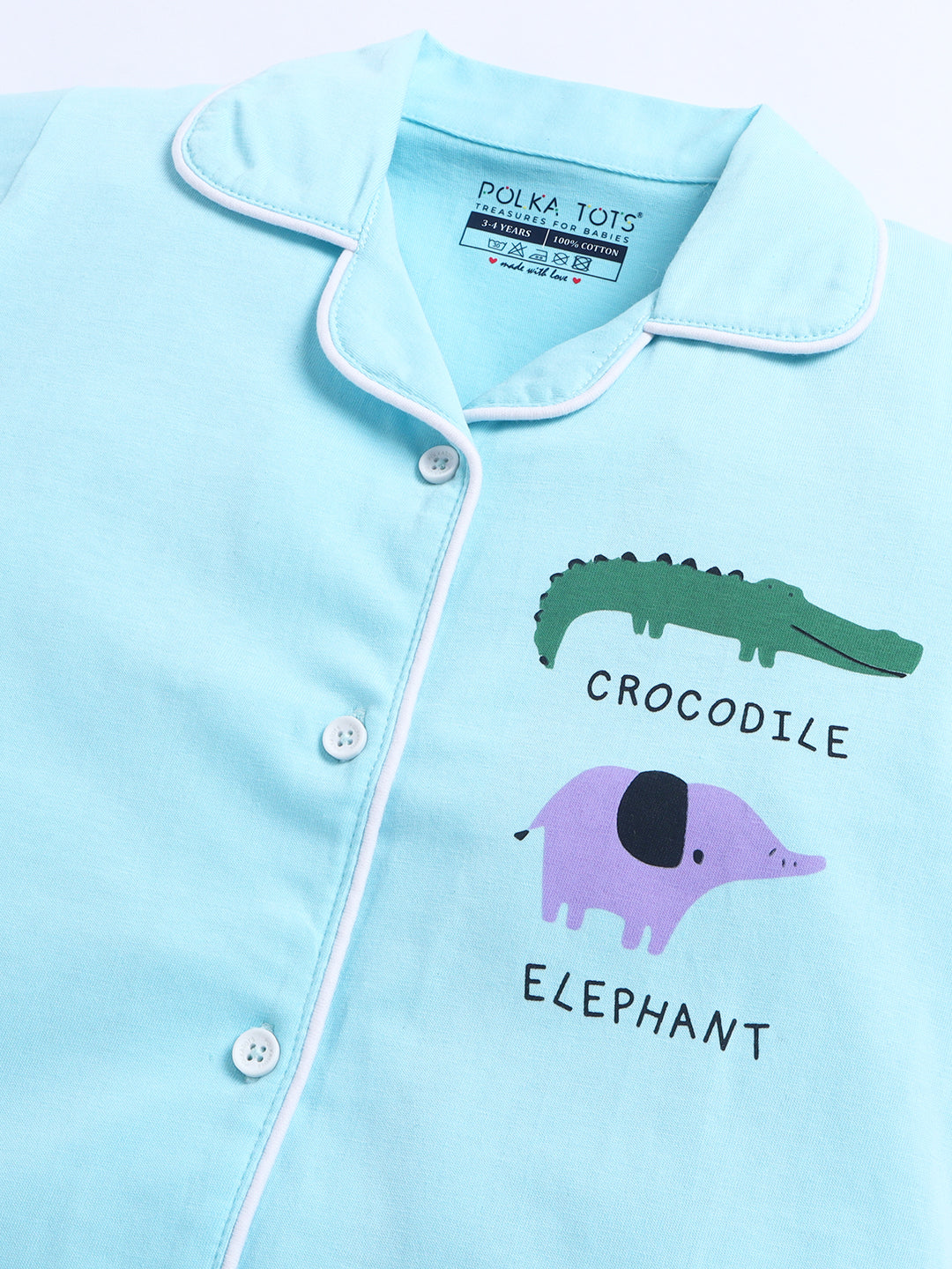 Light blue pajama top with crocodile and elephant designs and 'Polka Toys' branding.