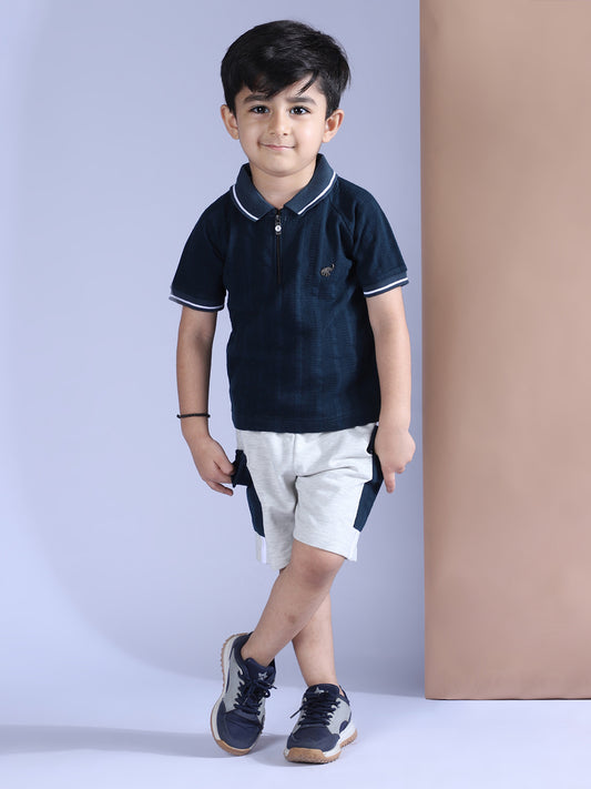 Child wearing a navy blue polo shirt and white shorts against a plain background