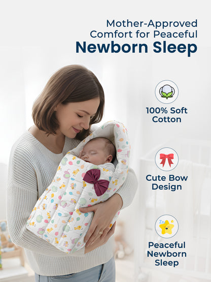 Woman holding a baby wrapped in a soft, colorful blanket with a bow design against a light background.