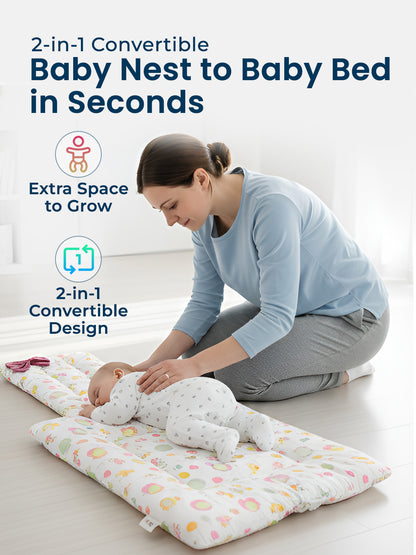 Woman with a baby on a 2-in-1 convertible baby nest and bed in a bright room.